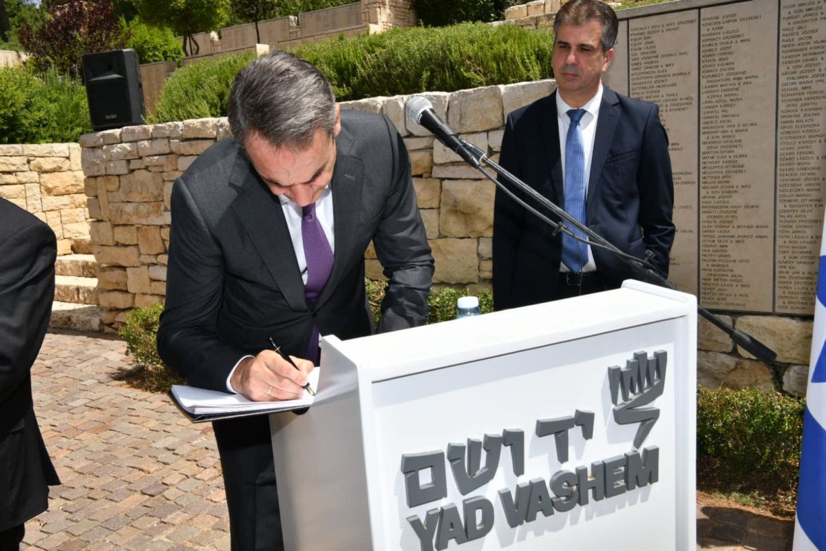The Greek Prime Minister signing the Yad Vashem guestbook in the Garden of the Righteous Among the Nations.